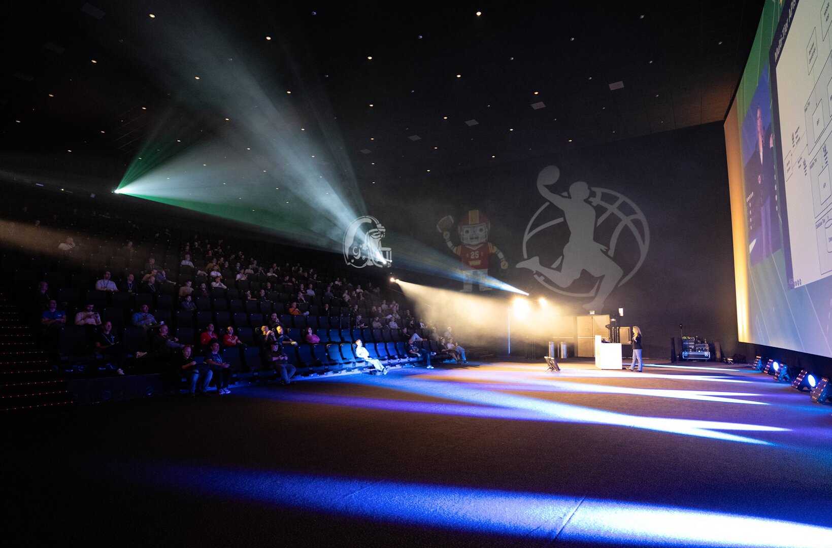 Presenter on stage at Techorama Netherlands in a cinema venue with dramatic lighting and audience in theater seats